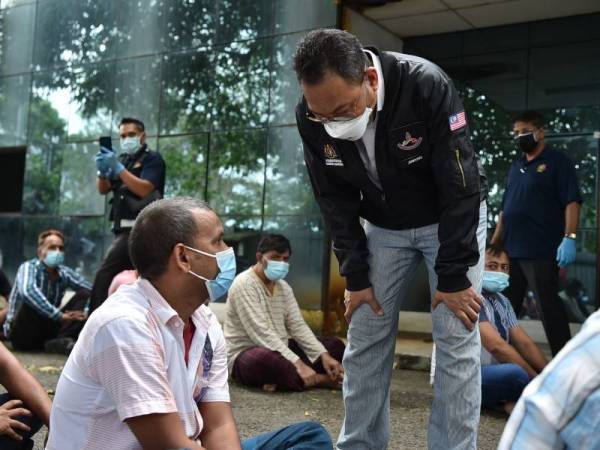 Awang (kanan) bertanyakan sesuatu kepada salah seorang pekerja asing sewaktu serbuan di sebuah asrama pekerja asing di Kawasan Perindustrian Dewani pada Sabtu.