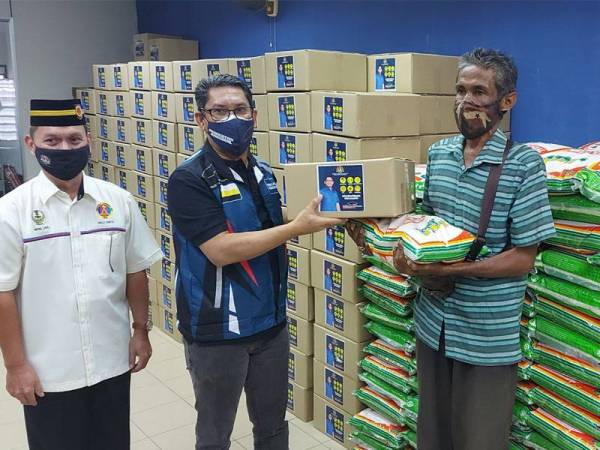 Ahmad Faizal (tengah) menyerah Bakul Makanan kepada salah seorang penduduk yang hadir.