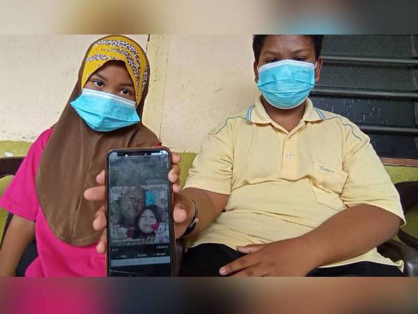 Mohammad Syahmil dan Nurhaniesya menunjukkan gambar Allahyarham ibu bapanya.