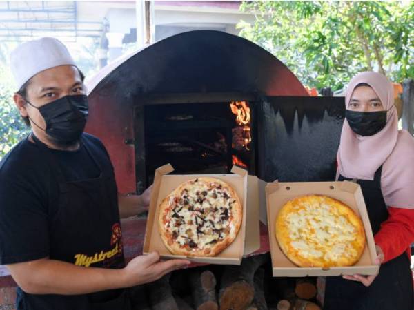 Pemilik Mystreet Pizza Kitchen Nur Hanani Ismail, 41, (kanan) dan adiknya Ahmad Najib Ismail, 33, menunjukkan piza durian Musang King dan piza daging salai yang dibakar dengan menggunakan dapur kayu ketika ditemui di Banggol Peradong, Manir. - Foto Bernama