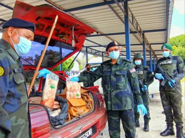 Hasan Basri (kanan) dan Azhari (kiri) menunjukkan ayam sejuk beku yang dirampas di pangkalan haram Pok Ngoh, Pengkalan Kubor, Tumpat pada Ahad.