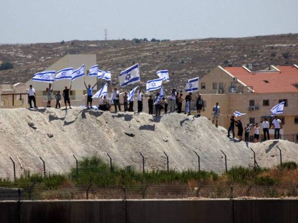 Pendatang Yahudi mengibarkan bendera Israel di penempatan haram Modiin Illit di Tebing Barat. -Foto Agensi