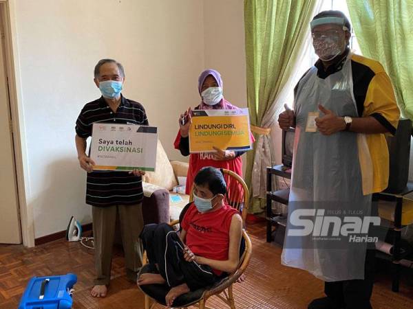 Dr Murallitharan (kanan) bersama pesakit dan keluarga selepas memberikan suntikan vaksin dalam Program Vaksinasi Rumah ke Rumah.