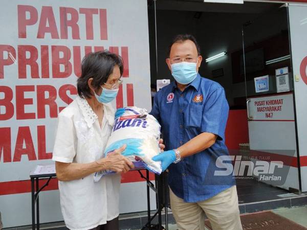 Osman (kanan) menyerahkan sumbangan bakul makanan di Kempas pada Khamis.