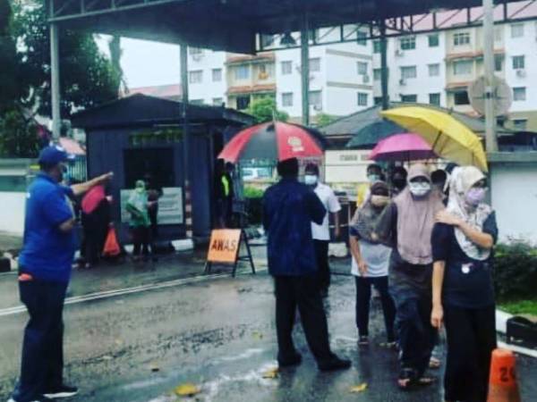 Orang ramai beratur dalam hujan untuk mengambil bantuan menerusi Program Runcit Truck N43 di Rumah Pangsa Permas Jaya, Pasir Gudang, pada Khamis.