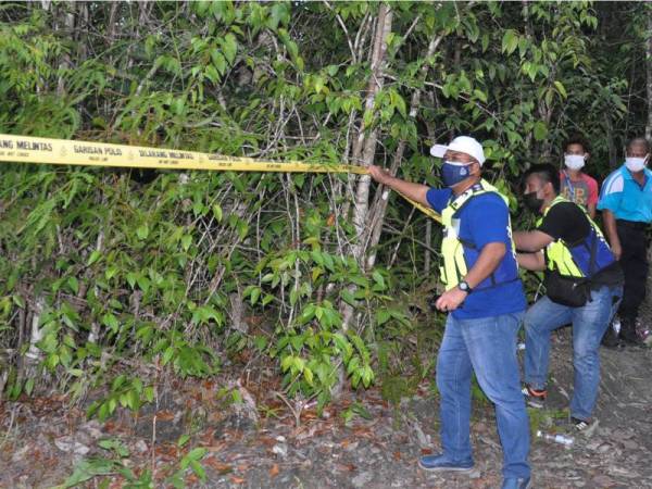 Superintendan Abdul Rozak Muhammad (kiri) membantu anggotanya menarik tali kawasan polis berhampiran mayat dipercayai warga emas, Yaacob Lateh, 83, yang ditemui meninggal dunia dalam hutan dekat Kampung Bukit Payong, Hulu Besut hari ini.  - Foto Bernama