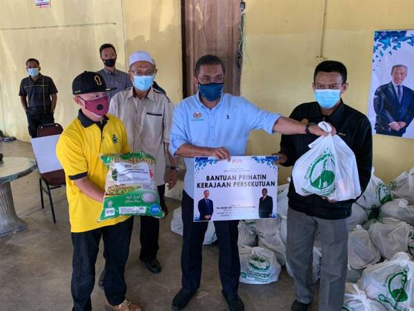 Takiyuddin (tengah) memberikan sumbangan berkenaan kepada penduduk di Kampung Tanjung Chat di sini pada Sabtu.