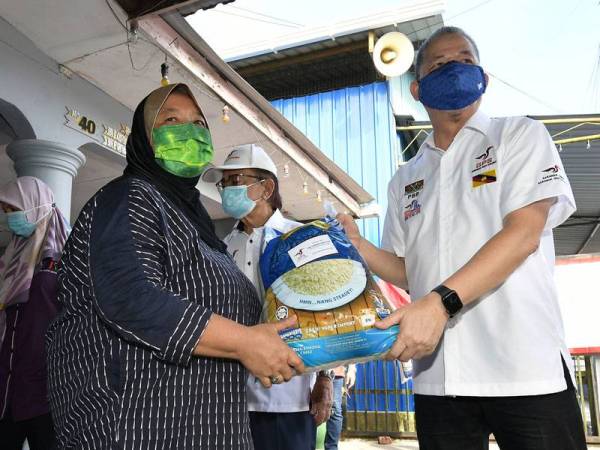 Fadillah Yusof (kanan) menyampaikan barangan keperluan asas makanan kepada wakil keluarga yang terkesan dengan PKP pada majlis penyerahan bakul makanan di Kampung Sungai Bedil Besar hari ini. -Foto Bernama