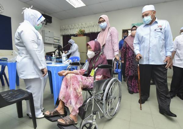 Ahmad Yakob (kanan) meninjau pelaksanaan proses vaksinasi pada Program Outreach Vaksinasi di Sekolah Menengah Kebangsaan Agama Falahiah, Pasir Pekan hari ini. -Foto Bernama