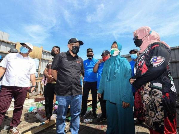 Kiandee (dua dari kiri) bertemu penduduk bagi menyampaikan bantuan kepada nelayan di Kampung Pulau Keniogan, Beluran pada Ahad.