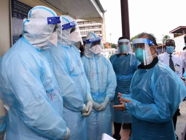 Perdana Menteri, Tan Sri Muhyiddin Yassin (kanan) beramah mesra bersama pegawa-pegawai perubatan Unit Forensik ketika meluangkan masa melawat Hospital Tengku Ampuan Rahimah pada Selasa. - Foto Bernama