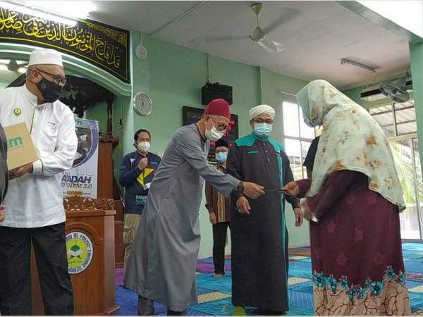 Zulkifli (tiga dari kanan) menyampaikan sumbangan kepada penerima pada Program Musa’adah 3.0 di Surau Al-Faizin, Taman Serai Permai, di sini, pada Selasa.