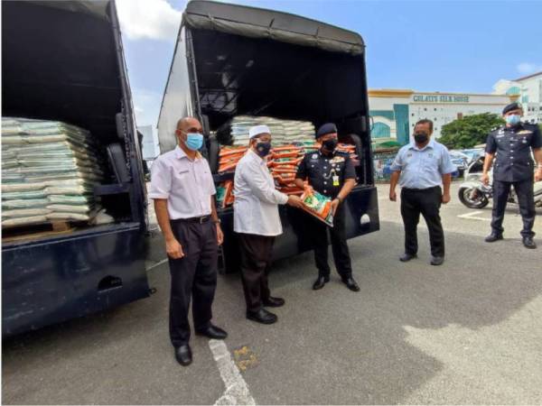 Ahmad Tarmizi (dua dari kiri) membuat simbolik penyerahan beras kepada Kamarul Zaman (tengah) di Ibu Pejabat MADACorp, Menara Peladang pada Selasa.