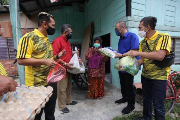 Zaitun (tengah) menadah tangan tanda bersyukur apabila menerima bakul makanan yang diberikan Aminuddin (dua dari kanan) dan pasukan Kongsi Rezeki di Kampung Chepor Dalam.