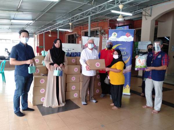 Mohd Chan (tiga dari kiri) bersama Shiela (dua dari kanan) menyerahkan sumbangan barangan keperluan asas kepada salah seorang penerima pada program itu di Masjid Jamek Saad Abu Waqqas Batu 4 pada Rabu.