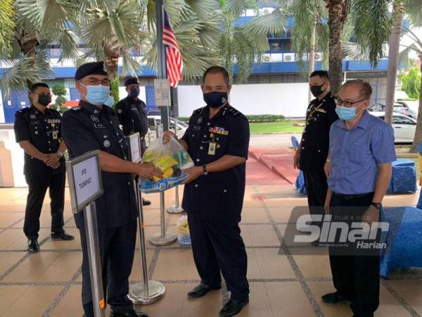 Abdullah (tengah) melakukan gimik serahan kepada wakil-wakil polis daerah untuk membawa pek makanan berkenaan pulang ke lokasi masing-masing untuk diedarkan.