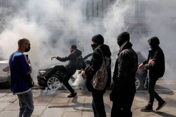 Para penunjuk perasaan menendang kanister gas pemedih mata yang dilemparkan oleh polis dalam tunjuk perasaan menentang arahan baharu Covid-19 di Paris pada Rabu. - Foto: AFP 