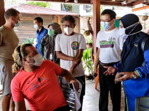 Dr Nor Azimi (dua dari kanan) berkata sesuatu kepada penerima vaksin di Pulau Kapas, Marang pada Khamis.