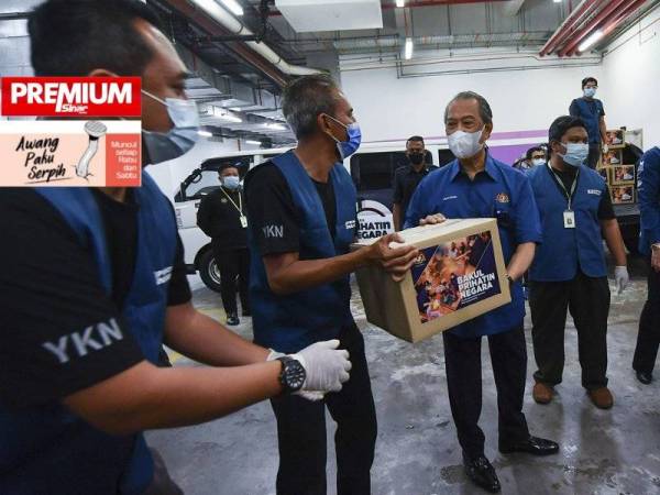 Perdana Menteri, Tan Sri Muhyiddin Yassin membantu sukarelawan menguruskan bakul makanan untuk penghantaran kepada golongan sasaran. - Foto Bernama