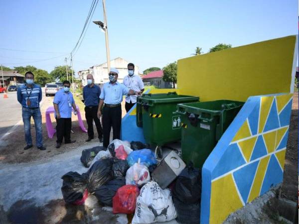 Rozali (tengah) menunjukkan sampah yang dibuang di luar tong sampah.