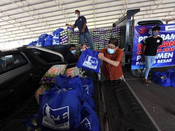 Timbalan Menteri Komunikasi dan Multimedia Datuk Zahidi Zainul Abidin merangkap Ahli Parlimen Padang Besar memasukkan barangan makanan ke dalam kenderaan pada majlis penyampaian sumbangan Bakul Makanan secara pandu lalu di Tapak Nat Bukit Keteri, hari ini.- Foto Bernama 