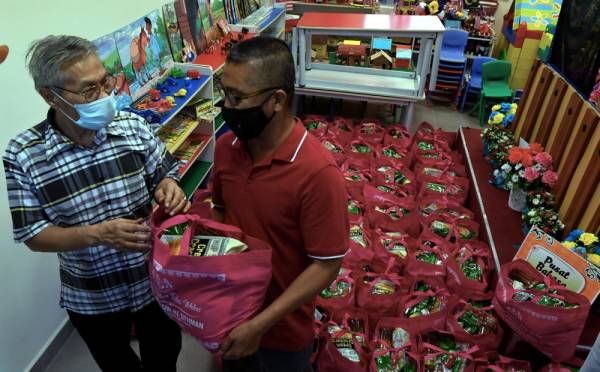 Mansor (kiri) menyumbangkan bekalan makanan kepada Pengerusi Kawasan Rukun Tetangga (KRT) Taman Jawi Indah, Abdul Razak Suid untuk diagihkan kepada keluarga terjejas. -Foto Bernama