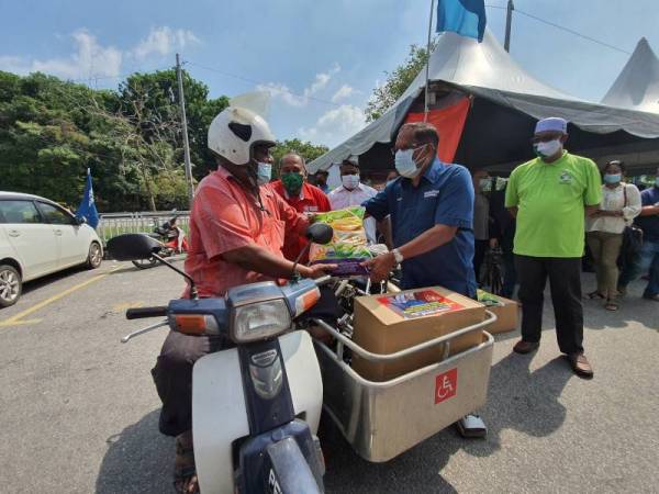 Shabudin menyampaikan bakul makanan kepada warga emas kurang upaya, Moh Hamidun, 66, ketika majlis penyampaian bakul makanan Pemulih peringkat Parlimen Tasek Gelugor pada Ahad.