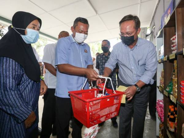  Menteri Besar Johor Datuk Hasni Mohammad (kanan) membantu salah seorang penerima mengambil keperluan asas yang diberikan oleh kerajaan Negeri Johor menerusi program Gobok Rakyat Johor di Pejabat Penghulu Mukim Jelutong Gelang Patah pada 11 Julai lalu. - Foto Bernama