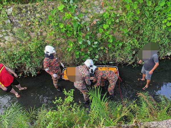 Anggota bomba membantu warga emas yang terjatuh ke dalam longkang ketika memanjat pokok nangka di Taman Kota Jaya Kota Tinggi pada Rabu.