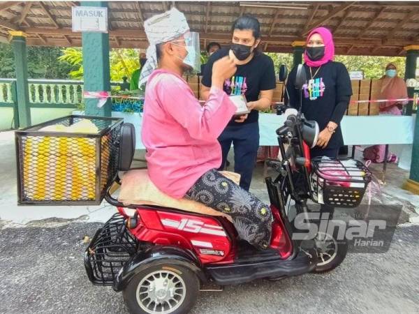 Mohd Faizul (dua dari kiri) dan isteri, Nor Baizura Ibrahim (kanan) menyerahkan daging korban kepada penerima di Masjid Mukim Paloh, Pasir Pekan, Tumpat pada Rabu.