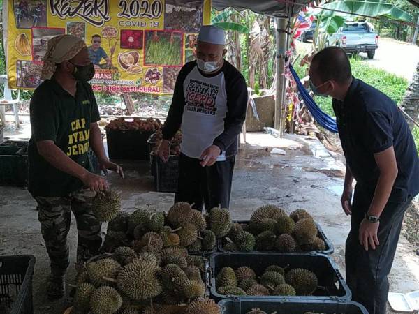 Mohd Firdaus (kiri) beri penerangan kepada Razman (tengah) mengenai isu durian yang tular sebelum ini di premis jualannya di Ijok, Larut pada Khamis.