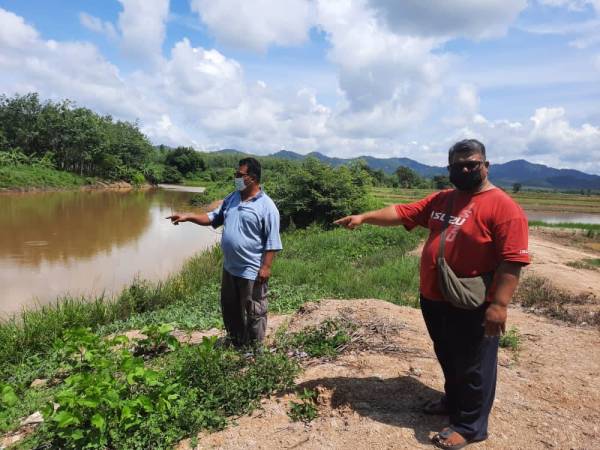 Mazli (kanan) menunjukkan tali air yang dijadikan takungan air untuk mengairi sawah-sawah yang berada di luar kawasan MADA di Padang Nyior, Kuala Nerang.