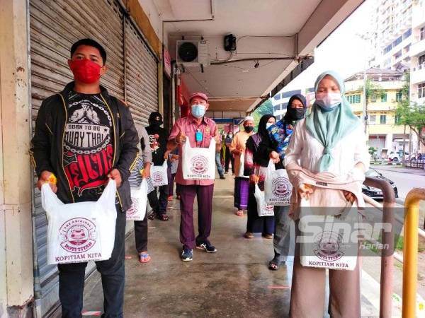 Nye Hua (tengah) dari Kopitiam Kita mengagihkan sumbangan makanan kepada 100 penduduk di sekitar bandar ini yang terjejas punca pendapatan akibat pandemik Covid-19.