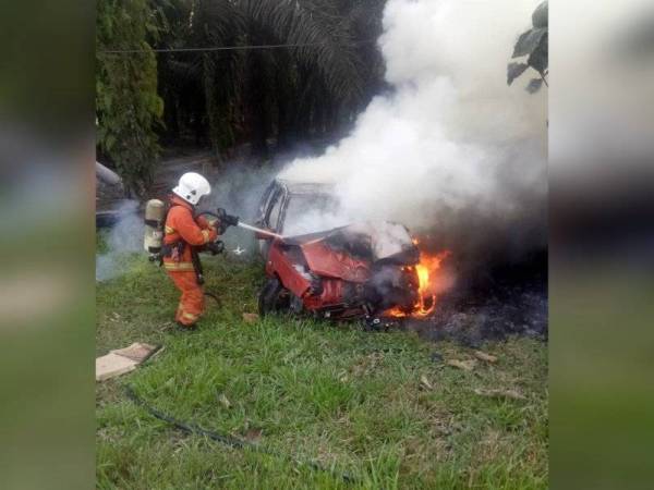 Anggota bomba memadamkan api pada Proton Iswara yang dinaiki pasangan suami isteri berkenaan di Ayer Tawar pada Isnin. - Foto ihsan JBPM Perak