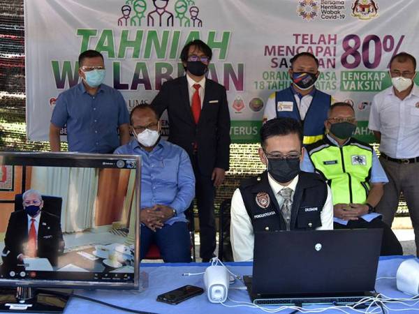 Annuar dalam sesi maya secara langsung bersama Pengarah Kesihatan Labuan, Dr Ismuni Bohari (depan) pada Program Imunisasi Covid-19 Kebangsaan (PICK) di Pusat Pemberian Vaksin (PPV) secara pandu lalu di Universiti Malaysia Sabah Kampus Antarabangsa Labuan pada Selasa. - Foto Bernama