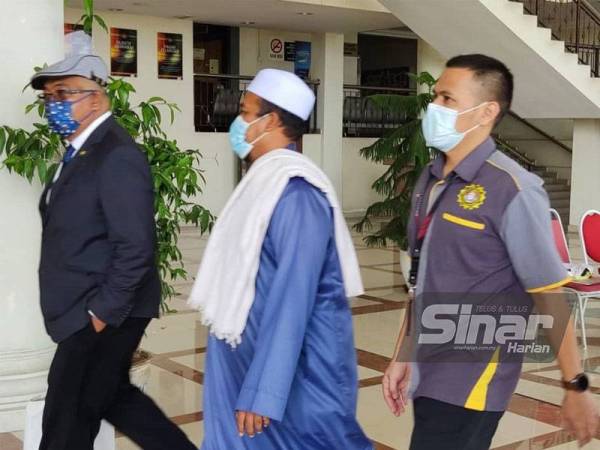 Mohd Idrus (tengah) bersama Saiful Izham (kiri) diiringi pegawai SPRM ke kaunter Mahkamah Alor Setar untuk membayar wang jaminan pada Rabu.