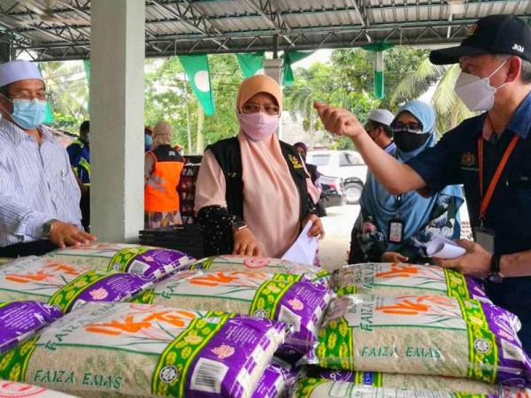 Mumtaz (tengah) bersama Said (kanan) dan Tuan Saripuddin (kiri) memeriksa sumbangan bakul makanan di PKD Selising, Pasir Puteh pada Rabu.