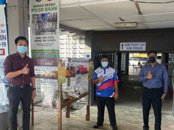 Dr Surender Benedict (kanan) bersama petugas Klinik Kesihatan Bandar Pekan di hadapan rak ' food bank' yang disediakan di klinik itu sejak dua minggu lalu.