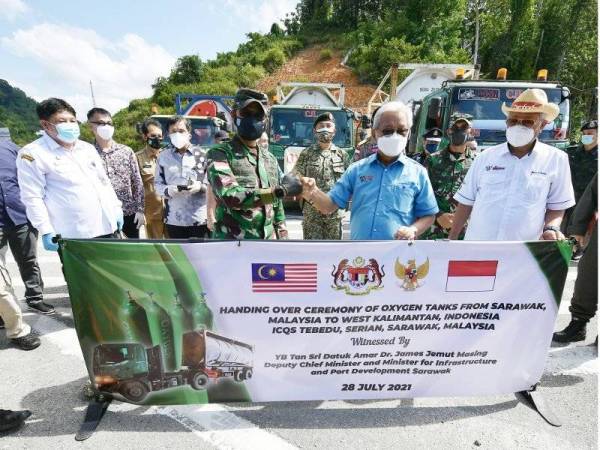 Masing menyerahkan bekalan oksigen kepada wakil kerajaan Indonesia, Jeneral Muhammad Nur Rahmad pada majlis penyerahan tangki oksigen daripada Sarawak kepada Privinsi Kalimantan Barat di ICQ Tebedu pada Rabu. - Foto Bernama