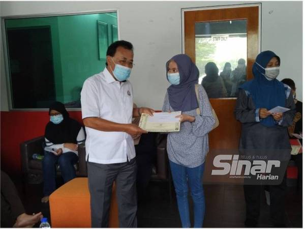 Osman (kanan) menyerahkan sumbangan kepada pelajar yang memperoleh keputusan cemerlang SPM di Kempas di sini pada Khamis.