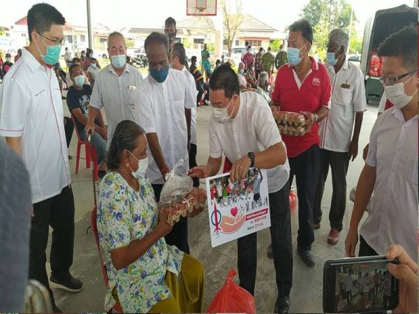 Kor Ming menyerahkan sumbangan kepada seorang penerima di Kampung Bemban, pada Jumaat.