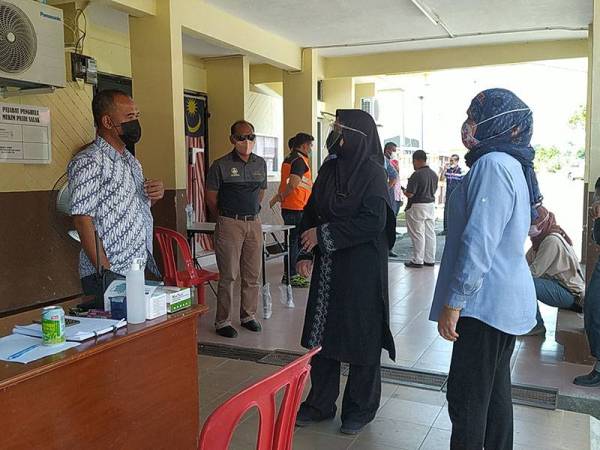 Barudin (kiri) memberikan taklimat mengenai pelaksanaan PKPD di empat lokaliti kepada Dr Wan Norashikin di Pusat Operasi Pejabat Penghulu Mukim Pasir Salak pada Sabtu.