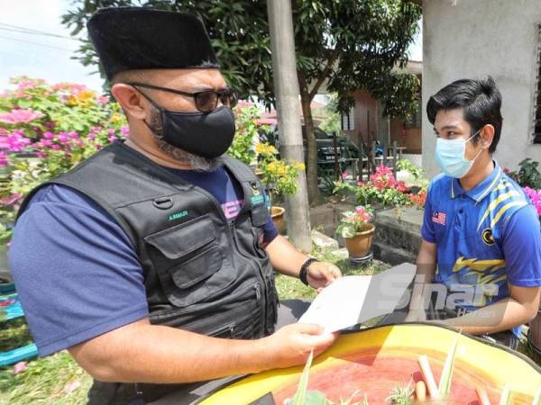 Dr Asmadi (kiri) menyampaikan bantuan kepada Muhammad Fariz bagi membolehkan remaja terbabit menyambungkan pengajiannya.