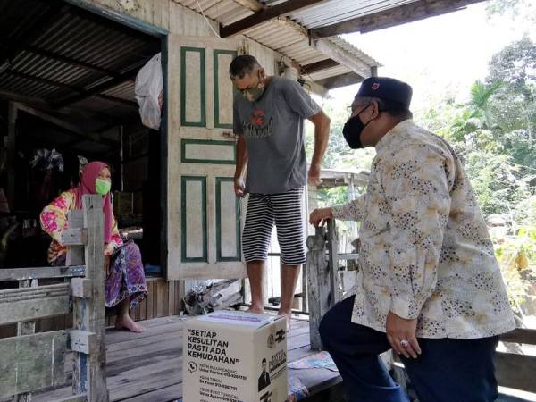 Mohd Khairuddin (kanan) menyerahkan sumbangan bakul makanan di Kampung Gemuruh pada Sabtu.