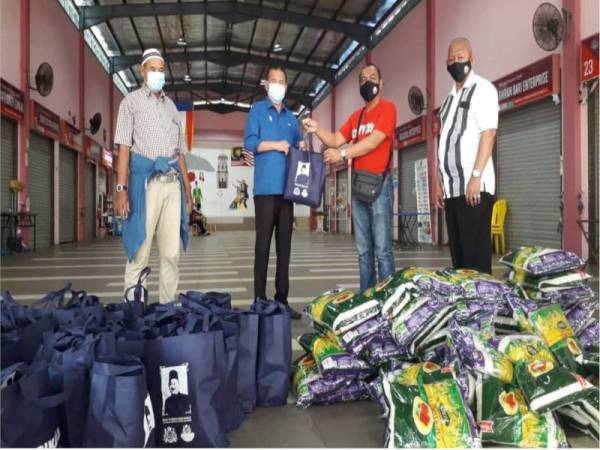 Che Zakaria (dua dari kiri) menyerahkan bakul makanan kepada ahli Persatuan Anak-anak Perantau Johor di Pasar Mufakat Sabah, Bandar Seri Alam, Pasir Gudang, pada Isnin.