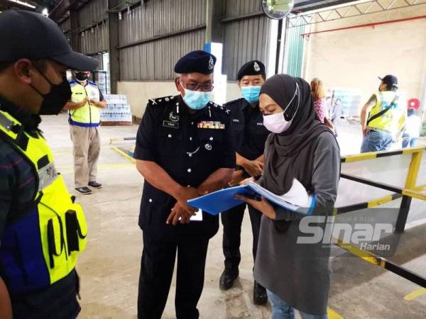 Yusuh (tengah) memeriksa dokumen berkaitan operasi kilang dalam Ops Patuh yang dijalankan di KKIA, Kota Kinabalu pada Isnin.