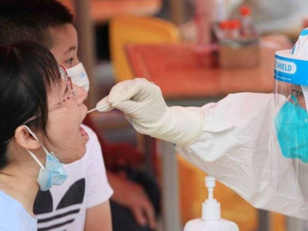 Gambar fail menunjukkkan seorang peawai membuat ujian saringan Covid-19 ke atas seorang penduduk di Nanjing, China. - Foto Getty Images