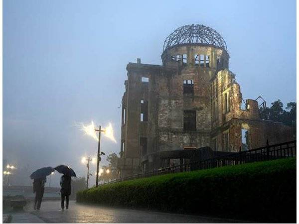 Pejalan kaki berjalan dalam hujan berdekatan Atomic Bomb Dome, di Hiroshima, barat Jepun. - Foto AP