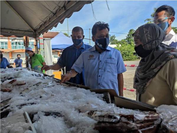 Che Abdullah (tengah) ketika melakukan tinjauan bekalan makanan dan rantaian pemasaran ikan dan mempromosikan ikan segar beku (Q’Fish) LKIM di Pasar Nelayan Seringgit. 