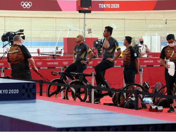 Azizulhasni dan Muhammad Shah Firdaus melakukan kayuhan regangan otot sambil diperhatikan ketua jurulatih berbasikal trek negara, John Beasley (kiri) selepas acara pecut semalam di Veledrome Izu, Shizouka pada Khamis. - Foto Bernama